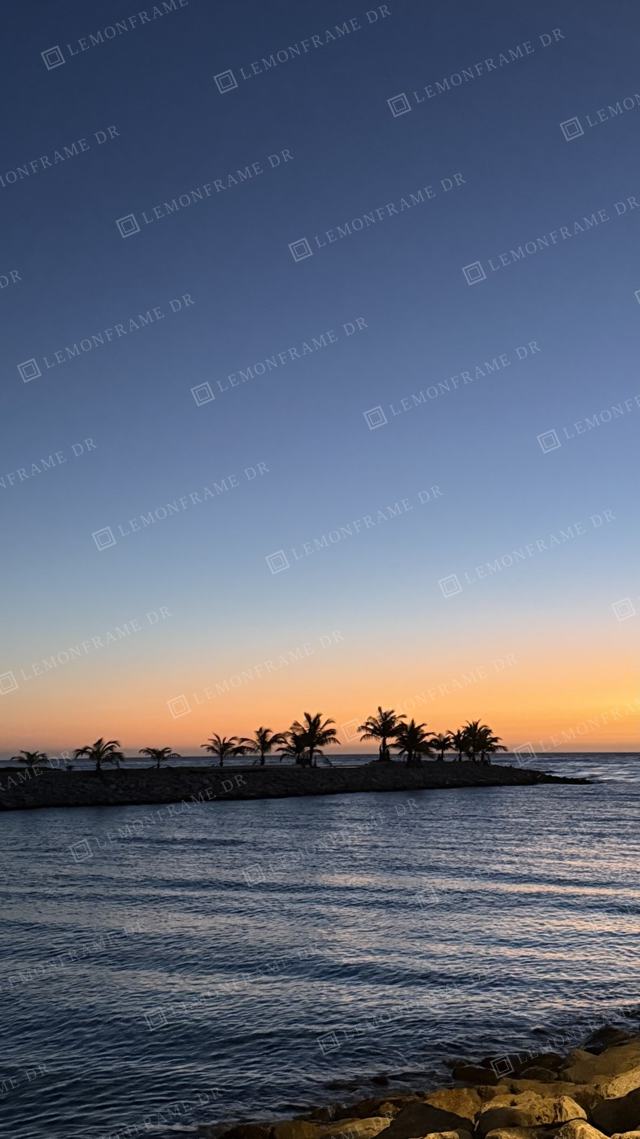 Islote con palmeras en el horizonte al anochecer